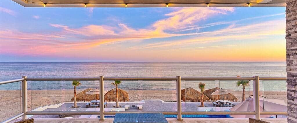 Sunset over the Sea of Cortez from a Six Palms villa balcony, with palapas on the beach below